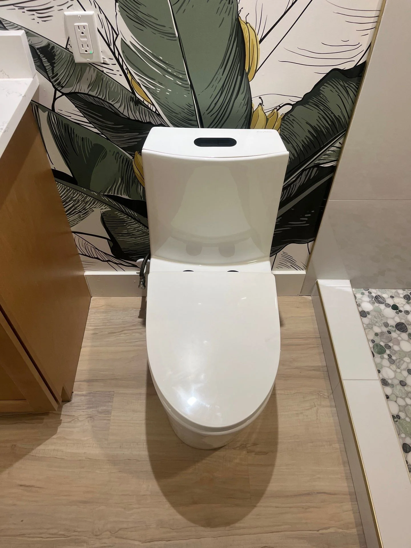 Modern bathroom toilet with banana leaf wallpaper accent