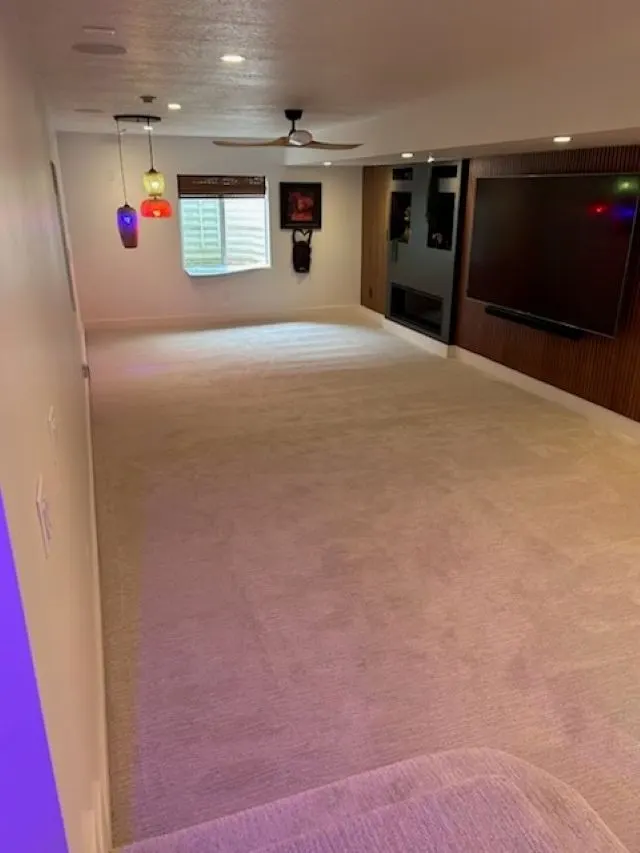 Finished basement entertainment area with large TV and wood accent wall